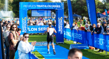Triathlete approaching the People's Triathlon finish arch at Mission Bay.