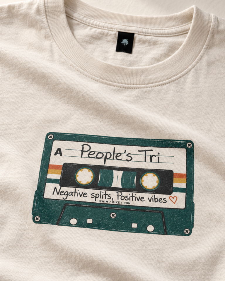Close-up of the retro cassette print on the cream People's Tri tee, reading Negative splits, Positive vibes.