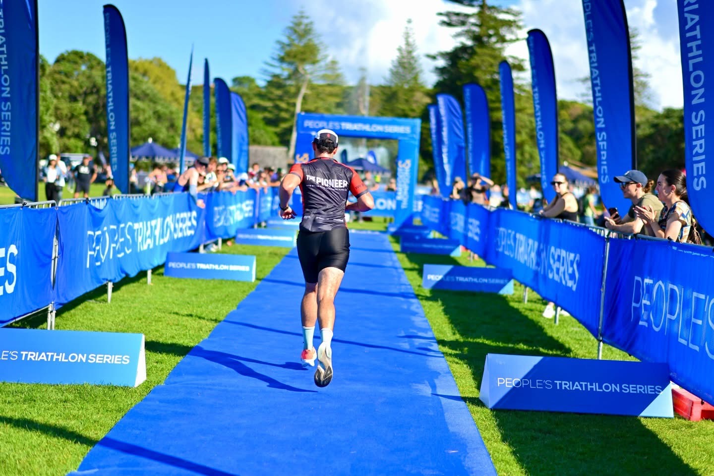 Athlete running along the blue carpet towards the People's Triathlon Series finish line